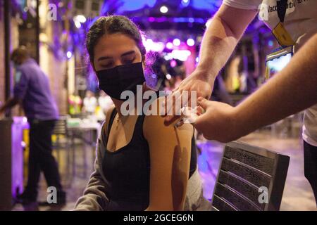 Londra, Regno Unito, 8 agosto 2021: Gabriella, 27 anni, riceve una dose del vaccino Pfizer al night club Heaven, che ha aperto le sue porte la domenica pomeriggio e la sera per una clinica pop-up walk-in vaccino. Il personale dell'NHS ha dato il vaccino Pfizer agli adulti che desideravano una prima o una seconda vaccinazione per migliorare il tasso di vaccinazione del distretto di Westminster, che è uno dei più bassi del paese. La pista da ballo è stata somministrata sulle stazioni di vaccinazione e la barra è stata utilizzata per prelevare dosi del vaccino in siringhe. Anna Watson/Alamy Live News Foto Stock