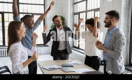 I dipendenti multirazziali entusiasti festeggiano la vittoria del team condiviso Foto Stock