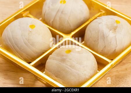 Pasticceria cinese o torta di luna ripiena di pasta di fagioli mungo dolce e tuorlo d'uovo salato in scatola d'oro su tavola di legno. Foto Stock