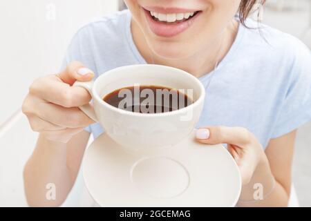 Happy woman beve un caffè espresso nero e sorride. Il concetto di problemi con il colore dei denti da cattive abitudini Foto Stock