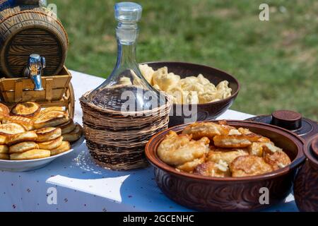 Lotto di frittelle, gnocchi e vino sul tavolo in cortile, primo piano, Ucraina. Cibo tradizionale ucraino Foto Stock