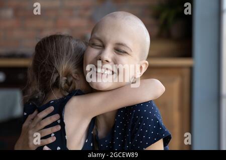 Felice eccitato giovane mamma cancro abbracciando bambino figlia Foto Stock