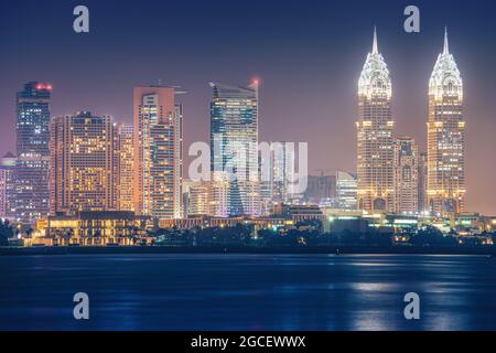 Vista notturna sul mare dell'area luminosa di Internet City a Dubai. Concetto di investimento immobiliare e costo dell'elettricità per l'illuminazione Foto Stock