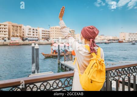 La donna, passeggero turistico, attende un traghetto sull'altro lato del canale del Dubai Creek con una maschera medica per prevenire l'infezione da covid-19 Foto Stock