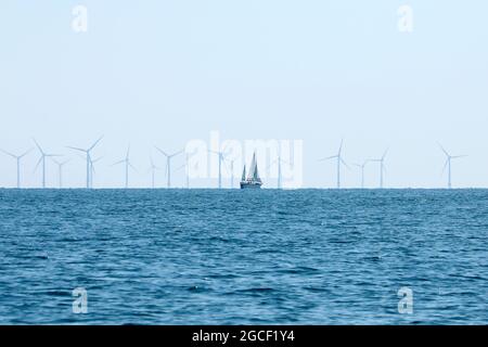 2021 08 04: Una barca a vela passa vicino al parco eolico offshore di Rampion Foto Stock