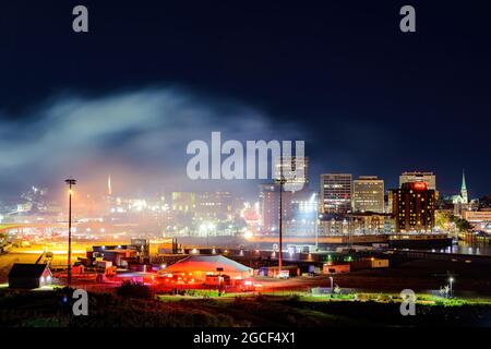 Saint John, NB, Canada - 1 agosto 2021: Una grande nuvola di fumo sulla città dopo un'esposizione di fuochi d'artificio. La nuvola si illumina di luce proveniente dalla città. Foto Stock