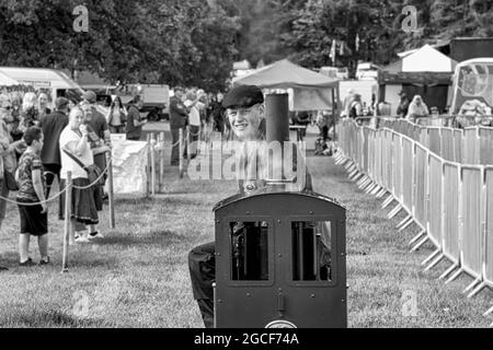 Il driver di un piccolo motore di trazione a vapore guarda la telecamera al traguardo di Harewood Steam Rally, Harewood, West Yorkshire, UK. Foto Stock