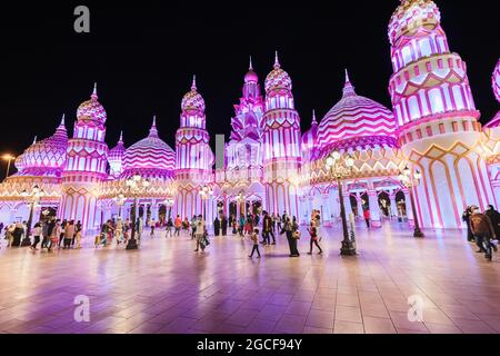 26 febbraio 2021, Emirati Arabi Uniti, Dubai: Visitatori e turisti camminano per le strade del Global Village illuminato in serata con padiglioni di molti c. Foto Stock