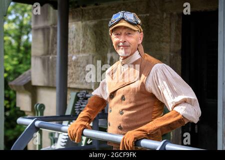 Henrichenburg, Waltrop, Germania. 8 agosto 2021. Un Signore elegante pone in abito ispirato aviazione. Vapore pieno davanti! I fan e i visitatori del Steampunk, molti in abiti retroventuristici, si riuniscono per la giornata senconda del festival´Steampunk Jubilee Market´ presso lo storico punto di riferimento dell'impianto di risalita di Henrichenburg sul canale Dortmund-EMS, oggi patrimonio industriale. Le vecchie strutture e le barche formano uno sfondo suggestivo per il festival all'aperto. Credit: Imageplotter/Alamy Live News Foto Stock