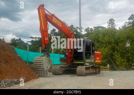Amaga, Antioquia, Colombia - Luglio 18 2021: Orange Crane Rimozione di una pila di Terra per la costruzione di una nuova strada Foto Stock