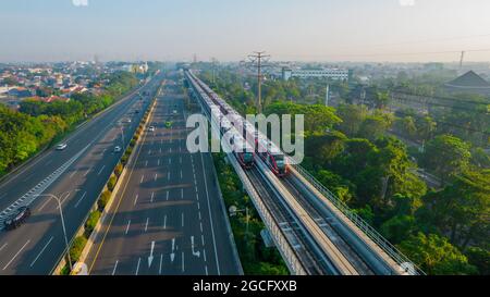 Vista aerea del treno LRT in movimento dalla stazione sui binari sopraelevati durante il periodo di prova con nube di rumore. Giacarta, Indonesia, 9 agosto 2021 Foto Stock
