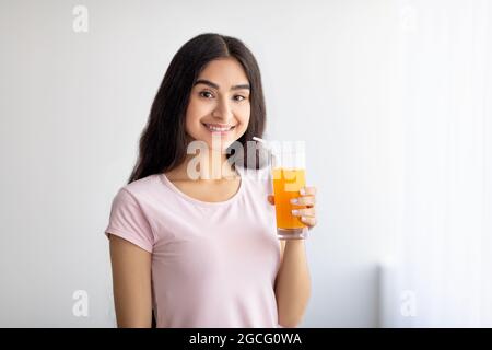 Bella donna indiana che beve succo di frutta fresca, gustando bevande detox a casa, spazio di copia. Slim Eastern Lady con gustosa bevanda al coperto. Livo sano Foto Stock