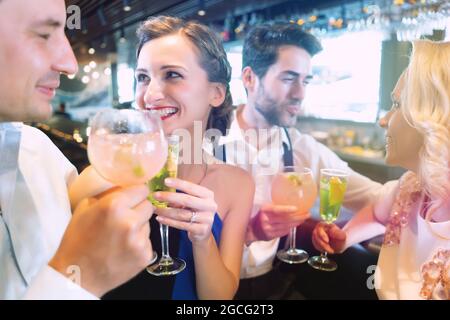 Gli uomini e le donne presso il bancone di un bar godendo le loro bevande Foto Stock