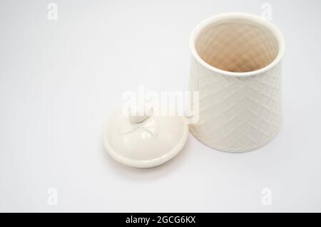 Una vista dall'alto di un piccolo contenitore bianco in ceramica con coperchio riempito di biscotti isolati su bianco Foto Stock