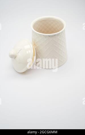 Una vista dall'alto di un piccolo contenitore bianco in ceramica con coperchio riempito di biscotti isolati su bianco Foto Stock