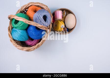 Un mucchio di palle tessili colorate di lana in un cesto di vimini su sfondo blu con uno spazio di copia Foto Stock