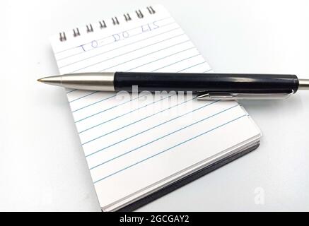 Primo piano di un piccolo quaderno aperto e di una penna con un punto  interrogativo scritto isolato su bianco Foto stock - Alamy