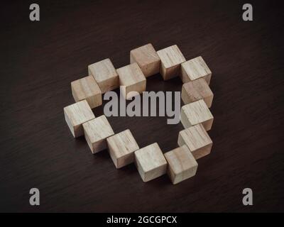 Blocchi di legno disposti a forma di cuore su sfondo di legno scuro, vista dall'alto. Concetto di amore e di coesistenza. Foto Stock