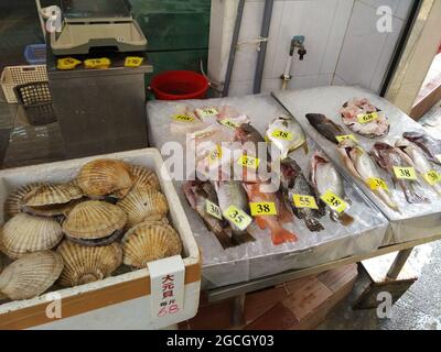 Pesce fresco come pesce e vongole su ghiaccio in un mercato umido all'aperto a Hong Kong vicino agli edifici Monster a Quarry Bay. Foto Stock