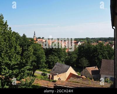 26 luglio 2021, Brandeburgo, Bad Belzig: Vista dal Castello di Eisenhardt delle case nel centro della città e la torre della Chiesa di Santa Maria. La chiesa romanica è stata costruita nella seconda metà del 13 ° secolo ed è ora sede del Museo dell'organo di Brandeburgo. Il complesso di castelli ben conservato, situato alla periferia della città, è un punto di riferimento della città che si può vedere da lontano. Menzionato per la prima volta in un documento del 997 dall'imperatore Ottone III come burgwardium belizi, il castello era stato probabilmente fondato cento anni prima da una tribù Elbslav. Il nome era un'espressione del desiderio che il castello fosse Foto Stock