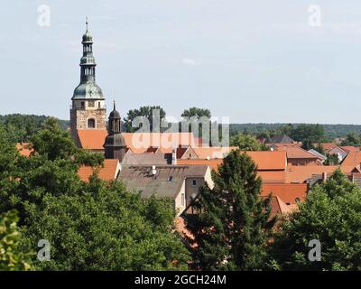 26 luglio 2021, Brandeburgo, Bad Belzig: Vista dal Castello di Eisenhardt delle case nel centro della città e la torre della Chiesa di Santa Maria. La chiesa romanica è stata costruita nella seconda metà del 13 ° secolo ed è ora sede del Museo dell'organo di Brandeburgo. Il complesso di castelli ben conservato, situato alla periferia della città, è un punto di riferimento della città che si può vedere da lontano. Menzionato per la prima volta in un documento del 997 dall'imperatore Ottone III come burgwardium belizi, il castello era stato probabilmente fondato cento anni prima da una tribù Elbslav. Il nome era un'espressione del desiderio che il castello fosse Foto Stock