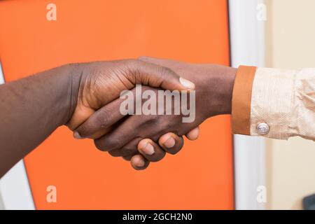Due mani africane sinistrorsa che si scambiano stretta di mano come segno di saluti, amicizia o affari di successo Foto Stock
