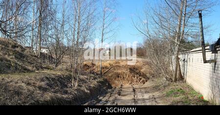 Grandi mucchi di terra e di sabbia si trovano sulla strada del villaggio. Paesaggio panoramico Foto Stock