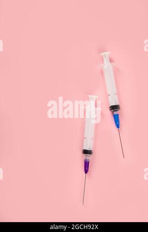Siringhe poste su sfondo rosa. Concetto medico e vaccinazione. Vista dall'alto, disposizione piatta, spazio per la copia Foto Stock