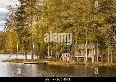 Piccola isola sul lago con una casa di campagna in Finlandia. Foto Stock