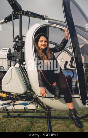 Sorridente ragazza preteen seduto in cabina di pilotaggio aperta di elicottero Foto Stock