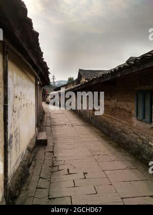 Un antico vicolo con una strada di pietra di ciottoli e vecchie mura in gesso casa nel bellissimo antico Lizhuang Foto Stock