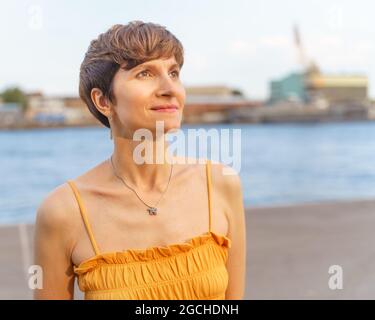Ritratto di bella donna matura in abito aperto con capelli corti in luce solare Foto Stock