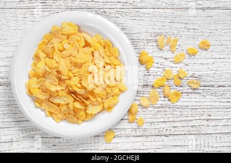 Cornflakes in piastra su vecchio tavolo di legno bianco, vista dall'alto Foto Stock