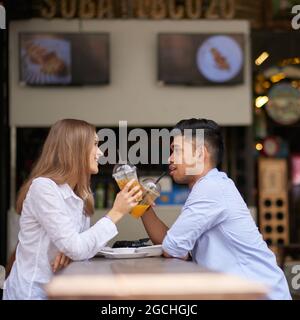 Diverse coppie seduti al tavolo del caffè, bevendo bevande rinfrescanti alla frutta e parlando godendo la loro prima data Foto Stock