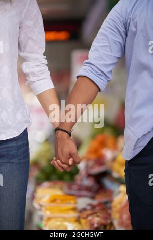 Immagine ritagliata di una giovane coppia che tiene le mani quando si fa shopping insieme nel supermercato Foto Stock