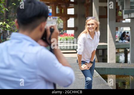 Sorridente giovane donna chiedendo al ragazzo di fotografarla per strada Foto Stock