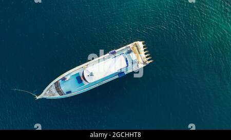 Top giù ultra ampia foto di barca grande velocità ancorata in tropicale baia esotica isola con mare cristallino turchese. Drone aereo Visualizza foto di velocità Foto Stock