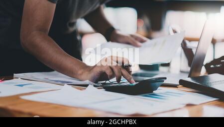 Primo piano contabile che lavora sulla scrivania utilizzando la calcolatrice per calcolare il report finanziario presso l'ufficio domestico Foto Stock