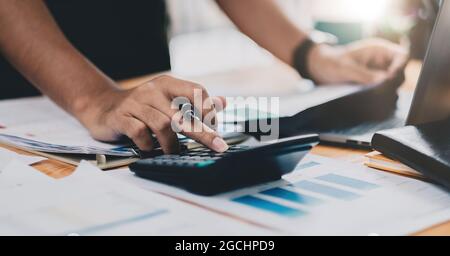 Primo piano contabile che lavora sulla scrivania utilizzando la calcolatrice per calcolare il report finanziario presso l'ufficio domestico Foto Stock