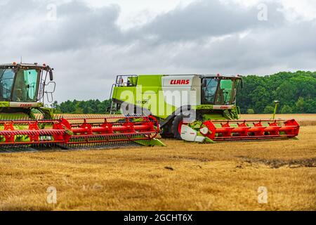 Mietitrebbie Lexion classe 750 parcheggiate su un campo stoppie in attesa che la pioggia si pulisca e finisca la mietitura Foto Stock