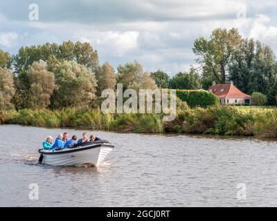 Gruppo di persone che navigano in una piccola barca in pendenza sul canale vicino a Grouw a Friesland, Paesi Bassi Foto Stock