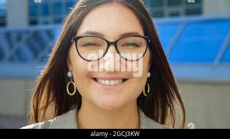 primo piano di una giovane donna che indossa occhiali sorridenti alla fotocamera Foto Stock