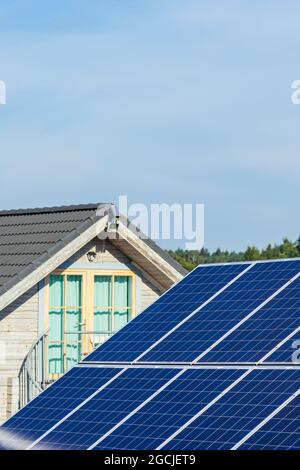 Pannelli solari sul campo in campagna con casa sullo sfondo. Impianto solare. Pannelli solari blu. Fonte alternativa di elettricità. Solare Foto Stock