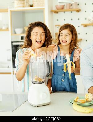 famiglia bambino cucina cibo figlia madre frutta frullato succo colazione felice insieme Foto Stock