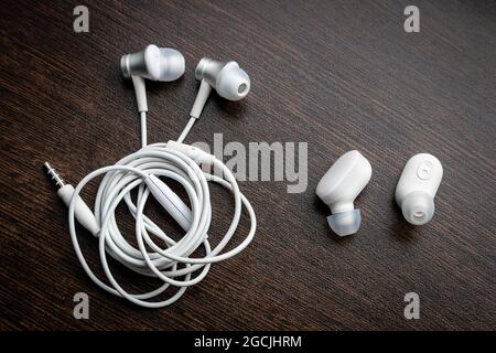 primo piano sulle cuffie wireless bluetooth bianche e sulle cuffie aggrovigliate Foto Stock