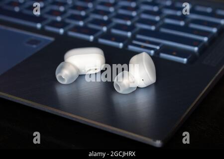 cuffie wireless bluetooth bianche sul guardaroba del computer portatile Foto Stock
