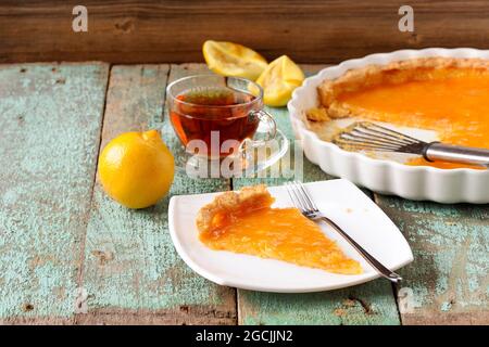Aprire la torta al limone, il tè, i limoni freschi e le bucce su tavole turchesi shabby orizzontali Foto Stock
