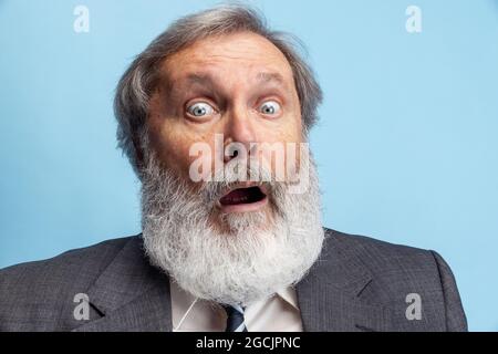 Professore pazzo, insegnante, uomo bearded grigio-testa che posa isolato su sfondo grigio studio. Concetto di occupazione professionale, lavoro, istruzione, divertente Foto Stock