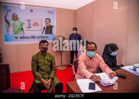 Non esclusivo: BARISHAL, BANGLADESH - 7 AGOSTO: I lavoratori registrano le persone prima di ottenere la dose di vaccino moderno Covid-19 durante una vaccin di massa Foto Stock