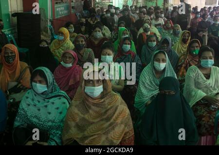 Non esclusivo: DHAKA, BANGLADESH - 8 AGOSTO: Cittadini del Bangladesh che indossano maschere facciali mentre attendono di ricevere una dose di vaccino moderno Covid-19 , durante Foto Stock